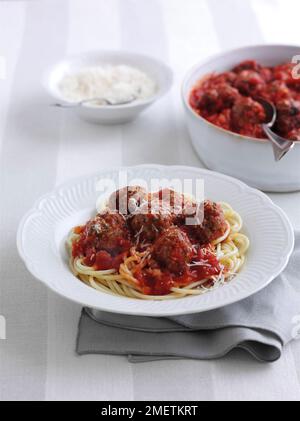 Teller mit Spaghetti mit Fleischbällchen in Tomatensoße, garniert mit geriebenem Käse Stockfoto
