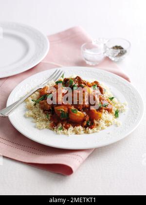 Lamm und getrocknete Aprikosen-Tagine garniert mit Petersilie und serviert mit Couscous Stockfoto