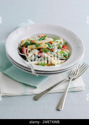 Pasta primavera, Penne Pasta mit Spargelspitzen, Zuckerschnabelerbsen, rote Paprika, Pinienkerne in cremiger Sauce, garniert mit Basilikumblättern Stockfoto