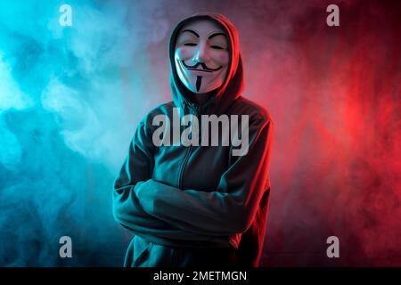 Hacker mit anonymer Maske, mit verschränkten Armen und einem bedrohlichen Blick Stockfoto