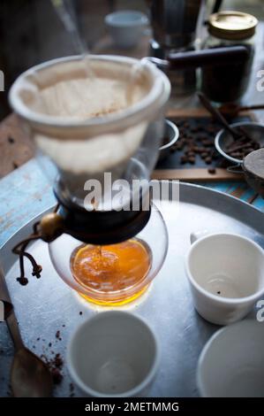 Caffe Touba, Kaffee läuft durch ein Tuch in eine Glaskanne, zwei leere Tassen Stockfoto