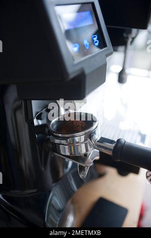 Mahlen des Kaffees und Ausgießen in einen Korb einer Espressomaschine (Portafilter) Stockfoto