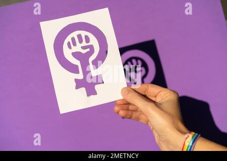 Eine Frau, die eine Zeichnung in der Hand hält, um die Gleichheit von Männern und Frauen zu rechtfertigen, lila Hintergrund, für Frauen zu kämpfen, weibliche Macht Stockfoto