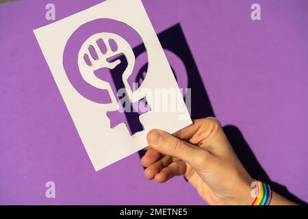 Eine Frau mit einer Zeichnung für die Gleichstellung von Männern und Frauen, lila Hintergrund, Kämpfe für Frauen, weibliche Stärke, LGTB-Flagge Stockfoto