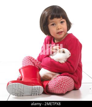 Ein Mädchen, das mit einem Kaninchen sitzt, 2 Jahre Stockfoto