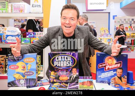 London, Großbritannien. 24. Januar 2023. TV-Moderator, Komiker und Magier Stephen Mulhern mit dem Schlagwort und in der Stimmung für ein Penny-Spiel am Asmodee-Stand. Die Spielzeugmesse öffnet ihre Türen in Kensington Olympia und präsentiert die neuesten Trends in der Spielzeugindustrie. Die Toy Fair ist die größte Fachmesse für Spielzeug, Spiele und Hobbys in Großbritannien mit mehr als 260 Ausstellern. Kredit: Imageplotter/Alamy Live News Stockfoto