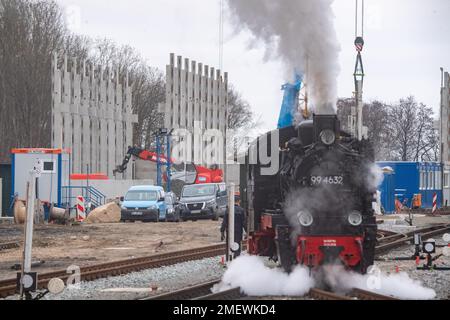 24. Januar 2023, Mecklenburg-Vorpommern, Putbus: Die Dampflokomotive 99 4632 der kleinen Eisenbahn „Rasender Roland“ fährt durch den Bahnhof in Putbus auf der Insel Rügen. Im Hintergrund wird ein neues Depot gebaut. Das Projekt „Railroad Experience Landscape“ umfasst den Bau eines neuen Schuppens und einer Betriebswerkstatt sowie einen Wasserturm für den Betrieb der Dampflokomotiven auf der Grundlage eines historischen Modells. Das Projekt „Railroad Experience Landscape“ hat ein Gesamtinvestitionsvolumen von über 40 Millionen Euro. Sie wird vom Bezirk Vorpommern-Rügen tog umgesetzt Stockfoto