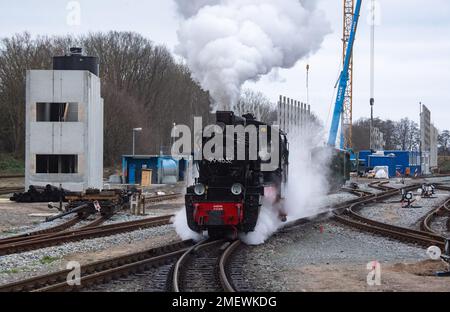 24. Januar 2023, Mecklenburg-Vorpommern, Putbus: Die Dampflokomotive 99 4632 der kleinen Eisenbahn „Rasender Roland“ fährt durch den Bahnhof in Putbus auf der Insel Rügen. Im Hintergrund wird ein neues Depot gebaut. Das Projekt „Railroad Experience Landscape“ umfasst den Bau eines neuen Schuppens und einer Betriebswerkstatt sowie einen Wasserturm für den Betrieb der Dampflokomotiven auf der Grundlage eines historischen Modells. Das Projekt „Railroad Experience Landscape“ hat ein Gesamtinvestitionsvolumen von über 40 Millionen Euro. Sie wird vom Bezirk Vorpommern-Rügen tog umgesetzt Stockfoto