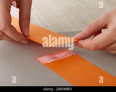 Papierhandwerk. Heimwerker-Tiermaske. Schritt 2 Anbringen von zwei Papierstreifen Stockfoto