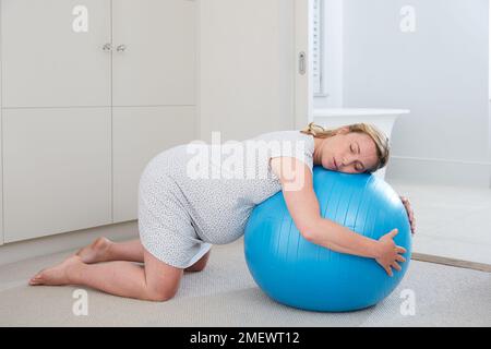 9 Monate/40 Wochen Schwangerschaft in der wehentätigkeit zu Hause. Knien mit einem Birthibg-Ball, aktive wehenphase. Stockfoto
