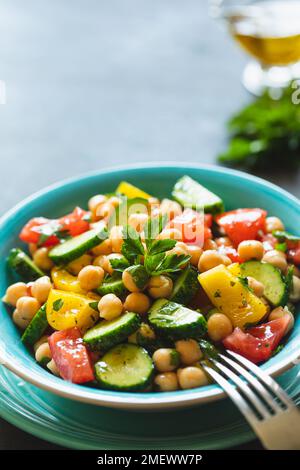 Kichererbensalat mit Tomaten, Gurke, Petersilie, Zwiebeln auf einem Teller, selektiver Fokus. Gesunde vegetarische Küche, orientalische und mediterrane Küche. Chic Stockfoto