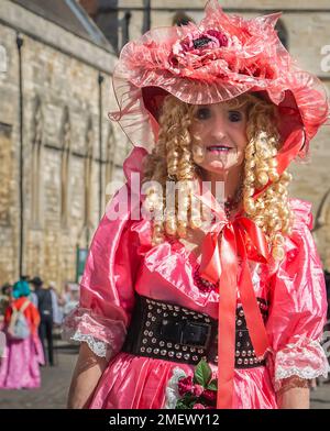 Porträt einer älteren Person mit langen blonden Korkenzieherlocken in einem pinkfarbenen antiken Kleid und einem großen pinkfarbenen Hut. Stockfoto