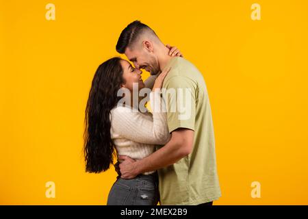 Romantisches Date. Fröhliche arabische Frau, die ihren großen Ehemann umarmt und küsst, Paar genießen Freizeit und zärtlichen Moment Stockfoto