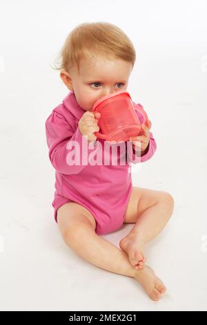 Baby in rosa Strampler trinken (Modell Alter - 9 Monate) Stockfoto