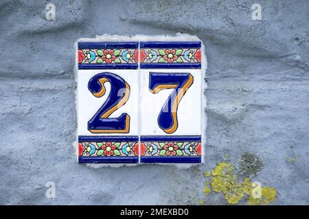 Eine Zahl auf einer grauen Zementwand mit blauen und orangefarbenen Mustern und dunkelblauen Linien Stockfoto