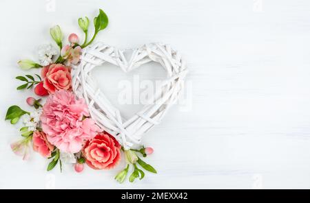 Wunderschöne Frühlingsblumen auf weißem Holzhintergrund. Festliche Blumenzusammensetzung mit Herz aus Holzästen. Valentinstag oder Muttertag Conce Stockfoto