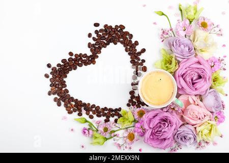 Festliches Konzept für Valentinstag oder Muttertag mit Blumen, einer Tasse Kaffee und Kaffeebohnen in Herzform auf weißem Hintergrund. Valentinstag gr Stockfoto
