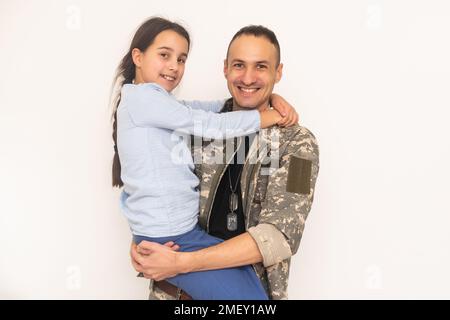 Liebevolle Mädchen Blick in die Kamera aus ihrem Vater wieder in camouflage Stockfoto