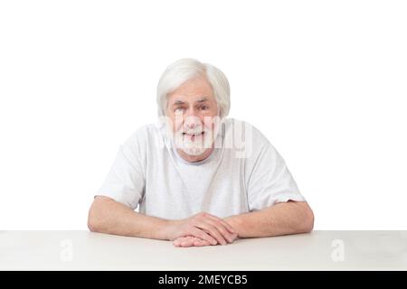 Horizontale Aufnahme eines fröhlichen, weißhaarigen Mannes, der auf einem Tisch auf weißem Hintergrund führt. Viel Platz zum Kopieren. Stockfoto