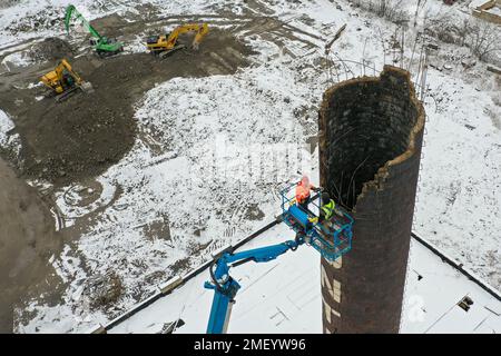 Detroit, Michigan, USA. 23. Januar 2023. Arbeiter reißen den Kamin des Kraftwerks bei Continental Motors ab. Es ist das letzte von mehreren Gebäuden, die abgerissen wurden. Das Werk stellte von 1912 bis 1955 Auto- und Flugzeugmotoren her und beschäftigte bis zu 8.000 Mitarbeiter. Kredit: Jim West/Alamy Live News Stockfoto