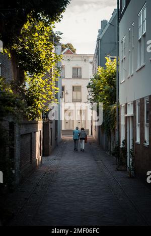 Ein vertikales Bild eines stilvollen älteren Ehepaars, das in einer engen Straße läuft Stockfoto