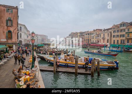Menschen essen im Freien und Boote parkten entlang eines Kanals im Herbst, Venedig, Italien. Stockfoto