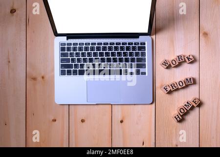 Offener Computer Laptop tragbar auf weißem leerem Display und Holzwürfel Brief auf Holztisch informativ und Kommunikation über die Arbeit von zu Hause Stockfoto