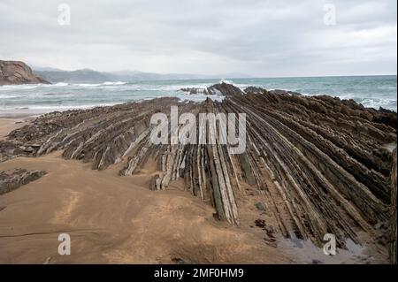 Blick auf steil geneigte Schichten von Flysch-geologischer Formation an der Atlantikküste bei Zumaia bei Ebbe, Baskenland, Spanien Stockfoto