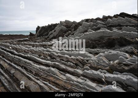 Blick auf steil geneigte Schichten von Flysch-geologischer Formation an der Atlantikküste bei Zumaia bei Ebbe, Baskenland, Spanien Stockfoto