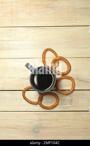 Eine Tasse mit Kaffee neben einem Bagel auf einem Plankentisch Stockfoto