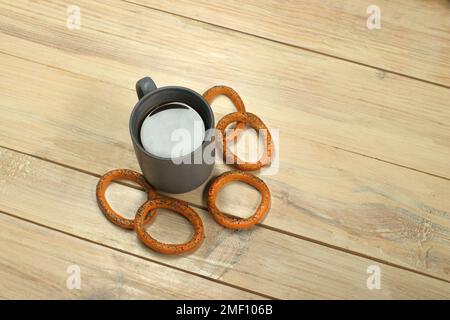 Eine Tasse mit Kaffee neben einem Bagel auf einem Plankentisch Stockfoto