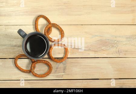 Eine Tasse mit Kaffee neben einem Bagel auf einem Plankentisch Stockfoto