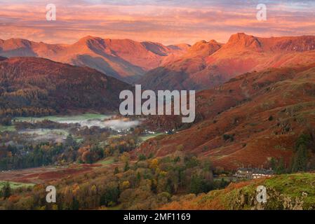 Wunderschönes Sonnenlicht am Morgen bei Sonnenaufgang auf den Langdale Pikes, von Loughrigg Fell im Lake District, Großbritannien aus gesehen. Stockfoto