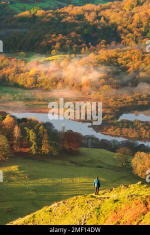 Einsamer Wanderer mit atemberaubender Aussicht an einem herbstlich nebeligen Morgen im Lake District, Großbritannien. Stockfoto