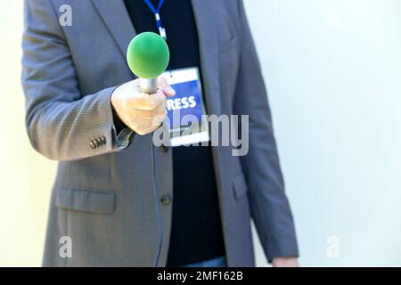 TV-Reporter bei Nachrichtenveranstaltungen, Pressekonferenzen oder Interviews mit Journalisten mit grünem Mikrofon. Broadcast-Journalismus-Konzept mit Kopierraum. Stockfoto