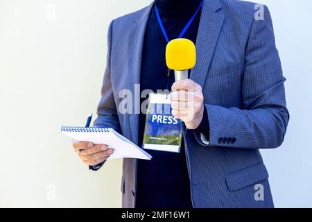 TV-Reporter bei Nachrichtenveranstaltungen, Pressekonferenzen oder Interviews mit Journalisten mit gelbem Mikrofon. Broadcast-Journalismus-Konzept mit Kopierraum. Stockfoto