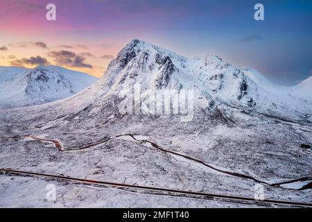 Die berühmten schottischen Berge waren bei Sonnenaufgang mit Schnee bedeckt. Glencoe, Schottland, Großbritannien. Stockfoto