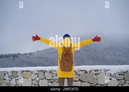 Ein ruhiger, sorgenfreier Mann mit ausgestreckten Händen steht auf der Suche nach Bergen, genießt die Aussicht, Zeit in der Natur. Stockfoto