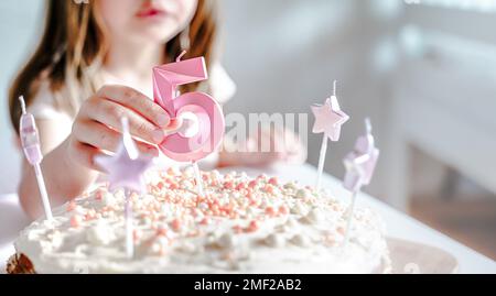 Große rosa Kerze mit 5 Ziffern auf hausgemachtem Kuchen. Kreative Gratulation zu fünf Jahren für ein Mädchen. Festliche Dekoration zum 5. Geburtstag, Belag, Dressi Stockfoto