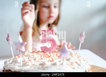 Große rosa Kerze mit 5 Ziffern auf hausgemachtem Kuchen. Kreative Gratulation zu fünf Jahren für ein Mädchen. Festliche Dekoration zum 5. Geburtstag, Belag, Dressi Stockfoto