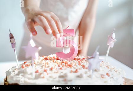 Große rosa Kerze mit 5 Ziffern auf hausgemachtem Kuchen. Kreative Gratulation zu fünf Jahren für ein Mädchen. Festliche Dekoration zum 5. Geburtstag, Belag, Dressi Stockfoto