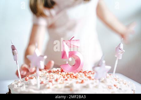 Große rosa Kerze mit 5 Ziffern auf hausgemachtem Kuchen. Kreative Gratulation zu fünf Jahren für ein Mädchen. Festliche Dekoration zum 5. Geburtstag, Belag, Dressi Stockfoto