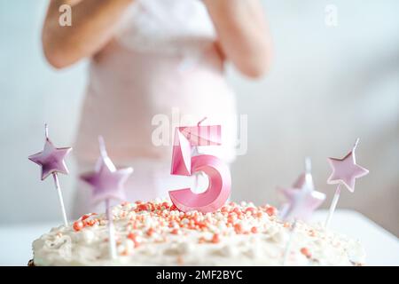 Große rosa Kerze mit 5 Ziffern auf hausgemachtem Kuchen. Kreative Gratulation zu fünf Jahren für ein Mädchen. Festliche Dekoration zum 5. Geburtstag, Belag, Dressi Stockfoto