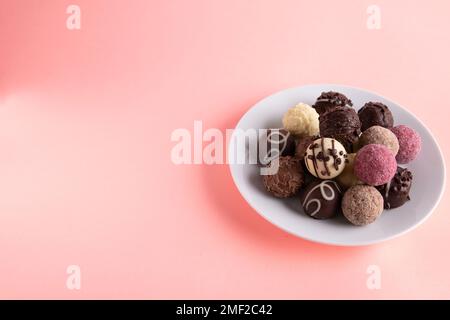 Fotografieren Sie verschiedene Süßigkeiten, die auf einem Teller auf einem farbigen Hintergrund liegen Stockfoto