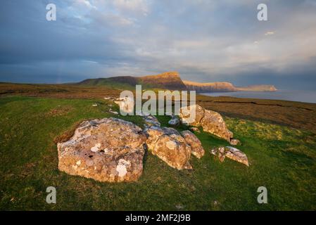 Dramatische Ausblicke auf die Klippen der Isle of Skye nahe Neist Point, während die schräge Sonne goldenes Licht über die Landschaft strahlt. Schottland, Großbritannien. Stockfoto