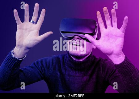 Der junge Mann benutzt einen Virtual-Reality-Betrachter. Modernes Porträt mit trendy Optik und leuchtenden Farben. Stockfoto