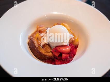Nahaufnahme von Kuchen mit Erdbeeren und Eis auf weißem Teller. Stockfoto
