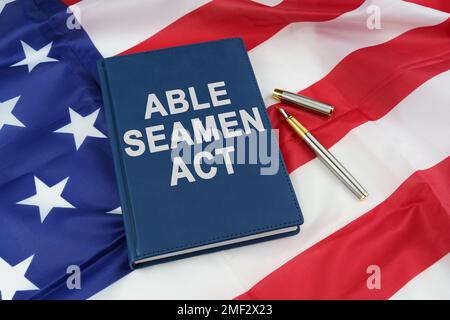 Regelkonzept. Auf der US-Flagge liegen ein Stift und ein Buch mit der Aufschrift "able Seamen Act" Stockfoto