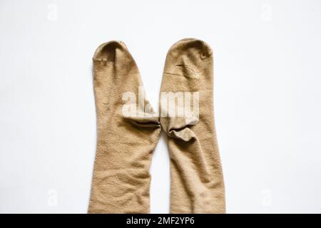 Schmutzige braune lange Frauensocken auf weißem Hintergrund, abgenutzte Socken Stockfoto