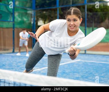 Frau, die während des Trainings auf dem Platz mit dem Padel spielt Stockfoto